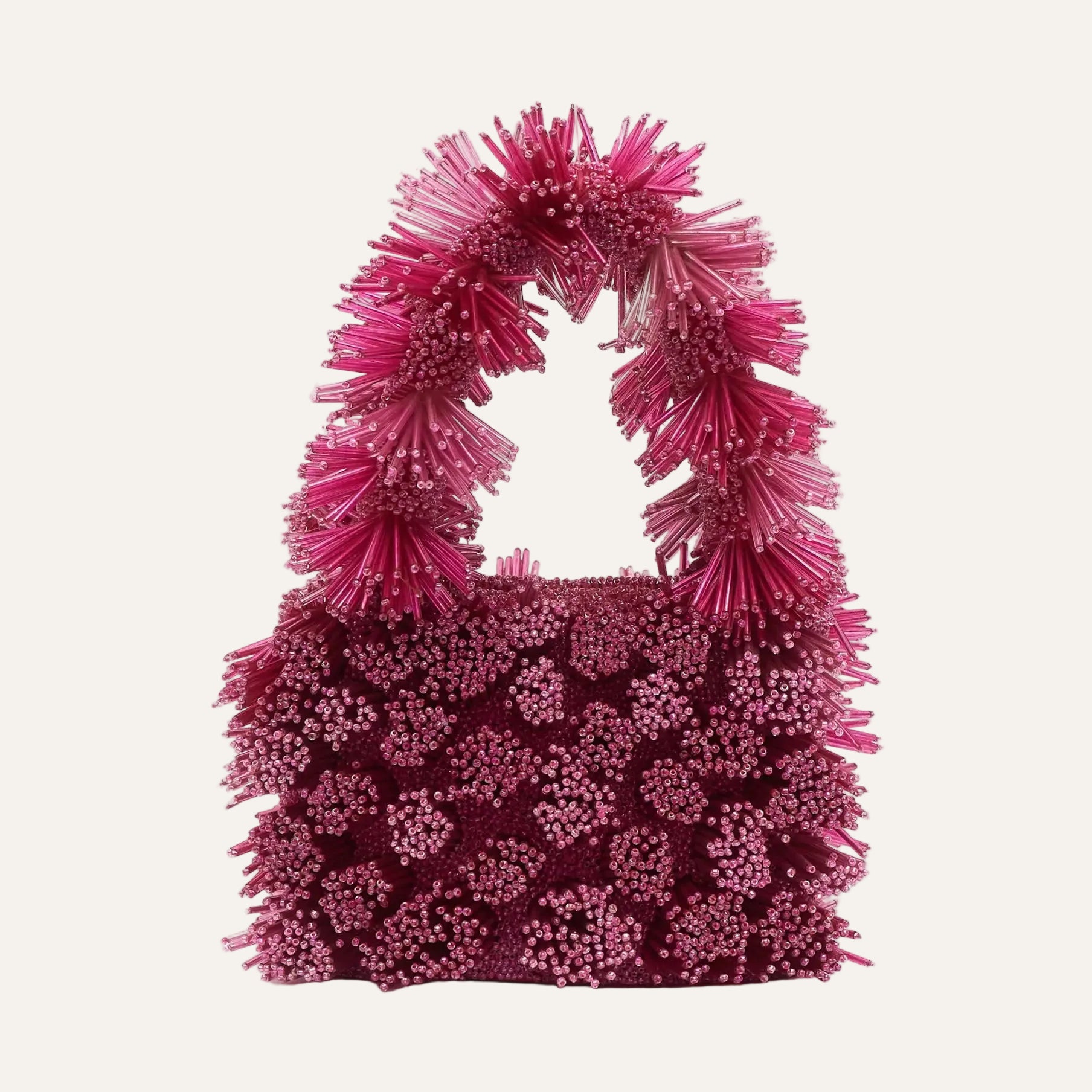 Pink textured handbag with fringe handle on a white background