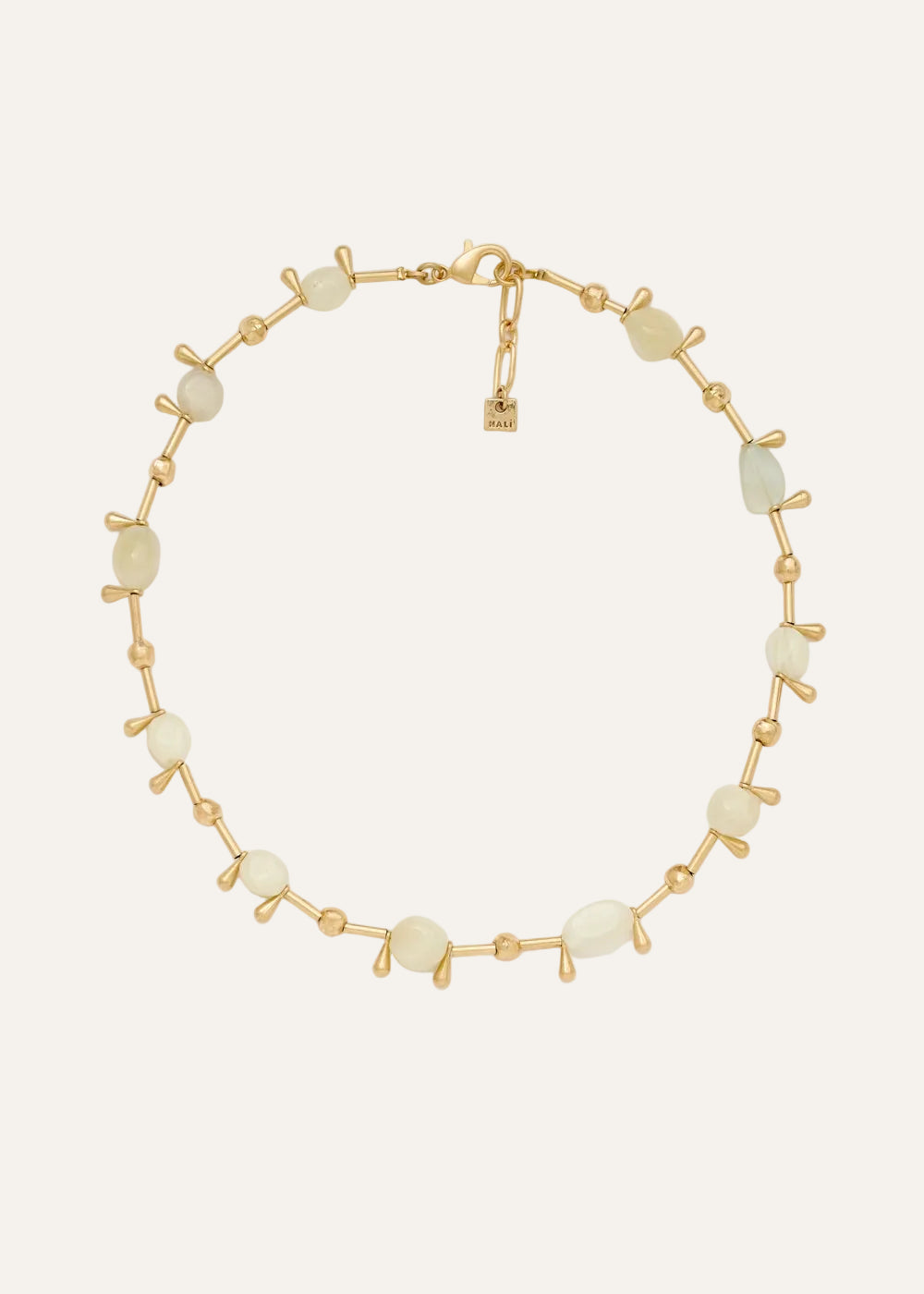 Gold bracelet with white beads on a light gray background